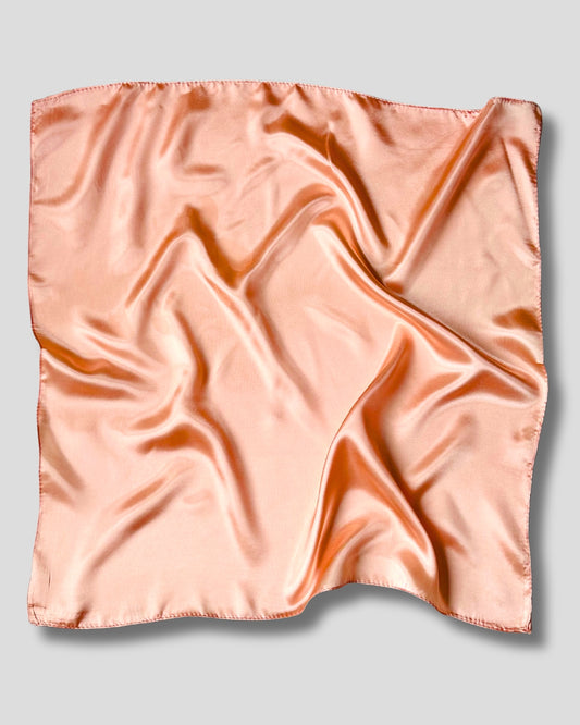 Pink peach satin square scarf on a light gray background