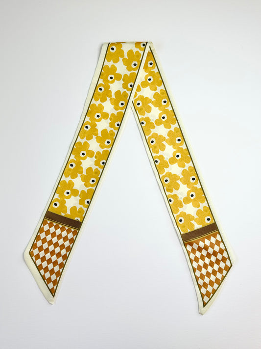 Yellow floral patterned ribbon scarf on a white background