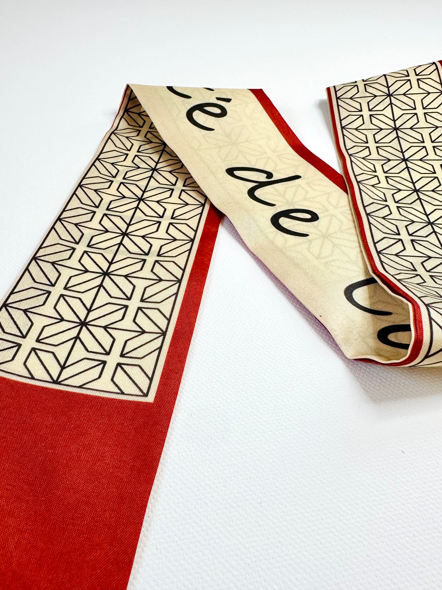 ribbon scarf with geometric pattern and text on a white background