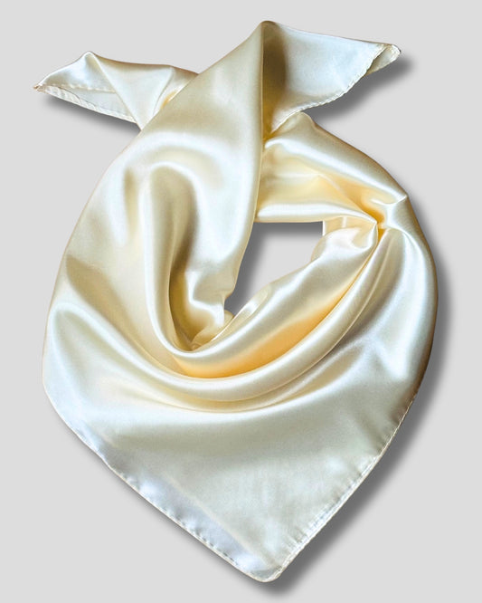 Cream-colored silk scarf folded into a triangle on a light gray background