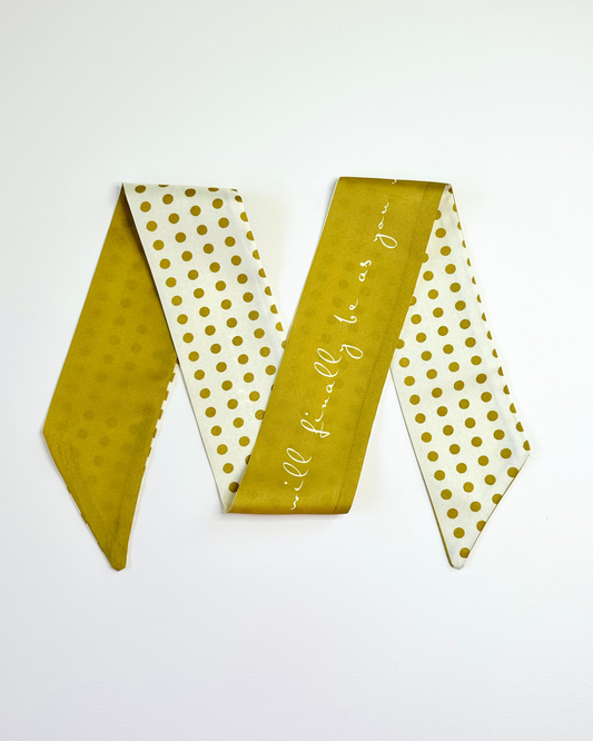 Gold and white polka dot ribbon scarf with text on a white background