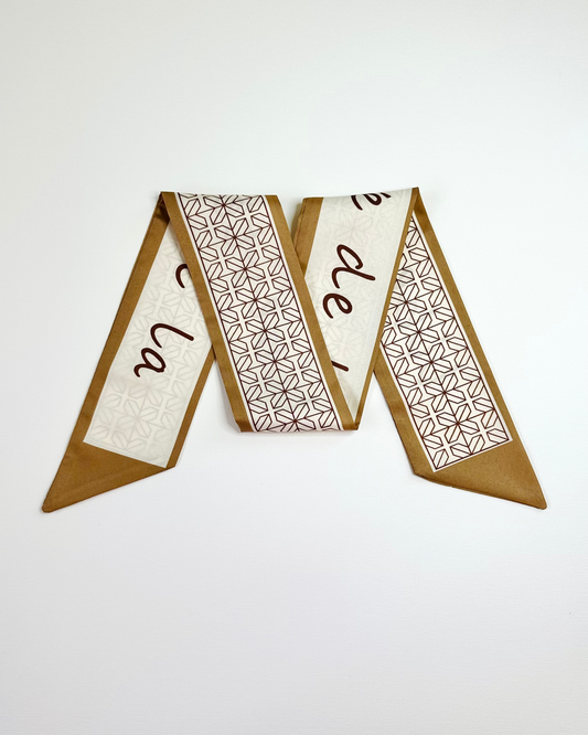 Decorative ribbon scarf with geometric patterns and text on a white background