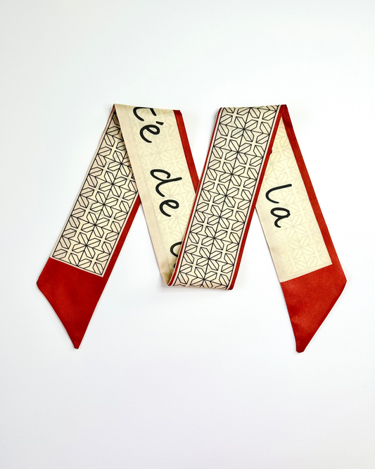 Decorative ribbon scarf with geometric pattern and text on a white background